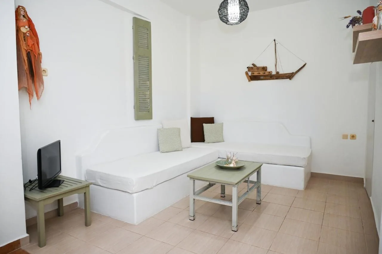 The living room of Navis Apartment with a built-in white sofa and a small boat on the wall