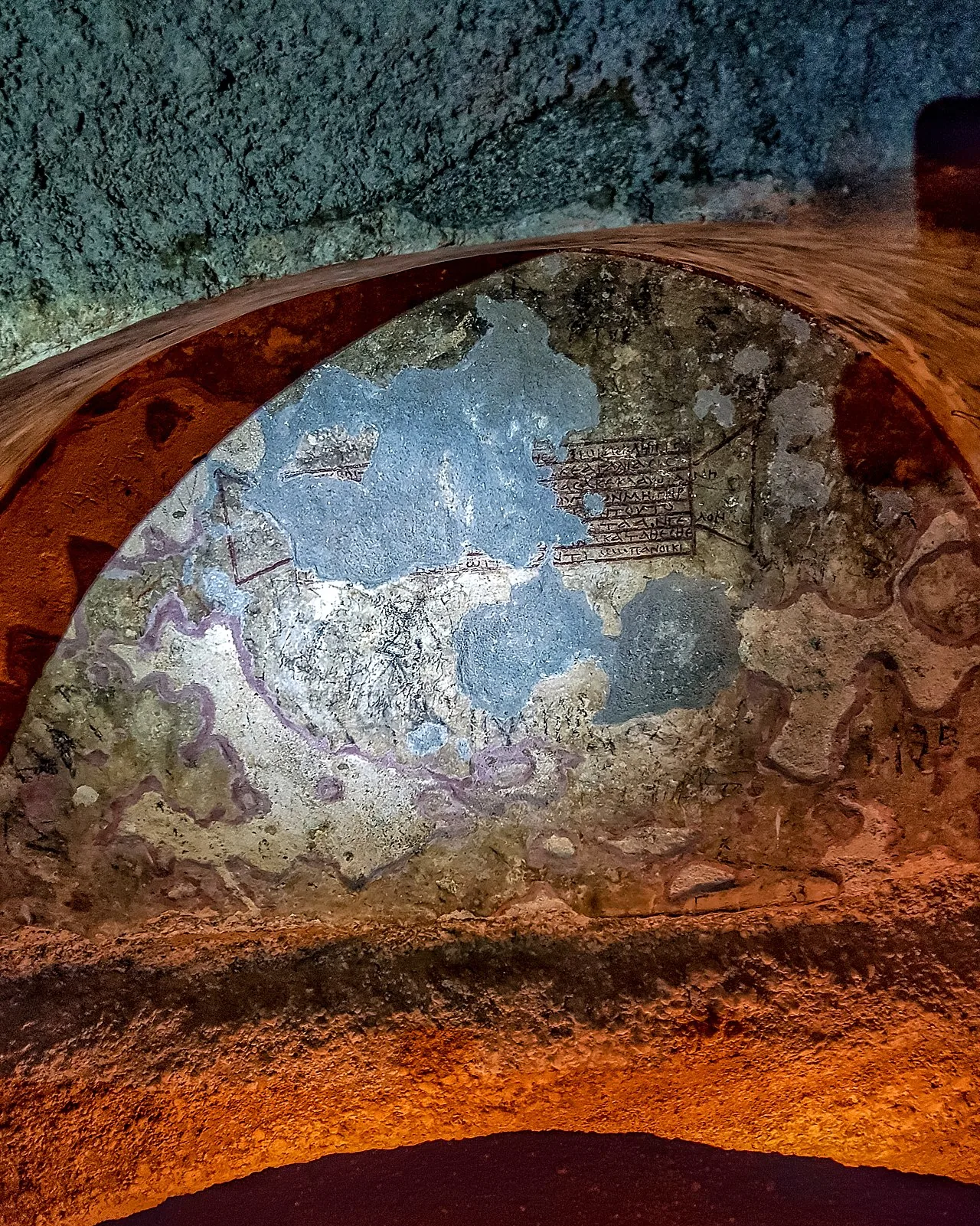Inside the catacombs of Milos at Tripiti, lit warm under a carved arch
