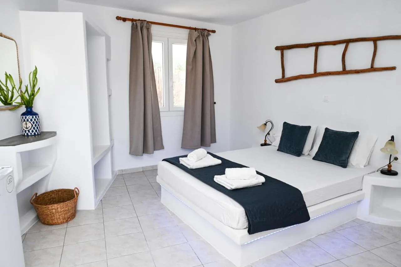 The bedroom of Navis Studio: a white bed with navy cushions, a wooden ladder on the wall, a window with brown curtains