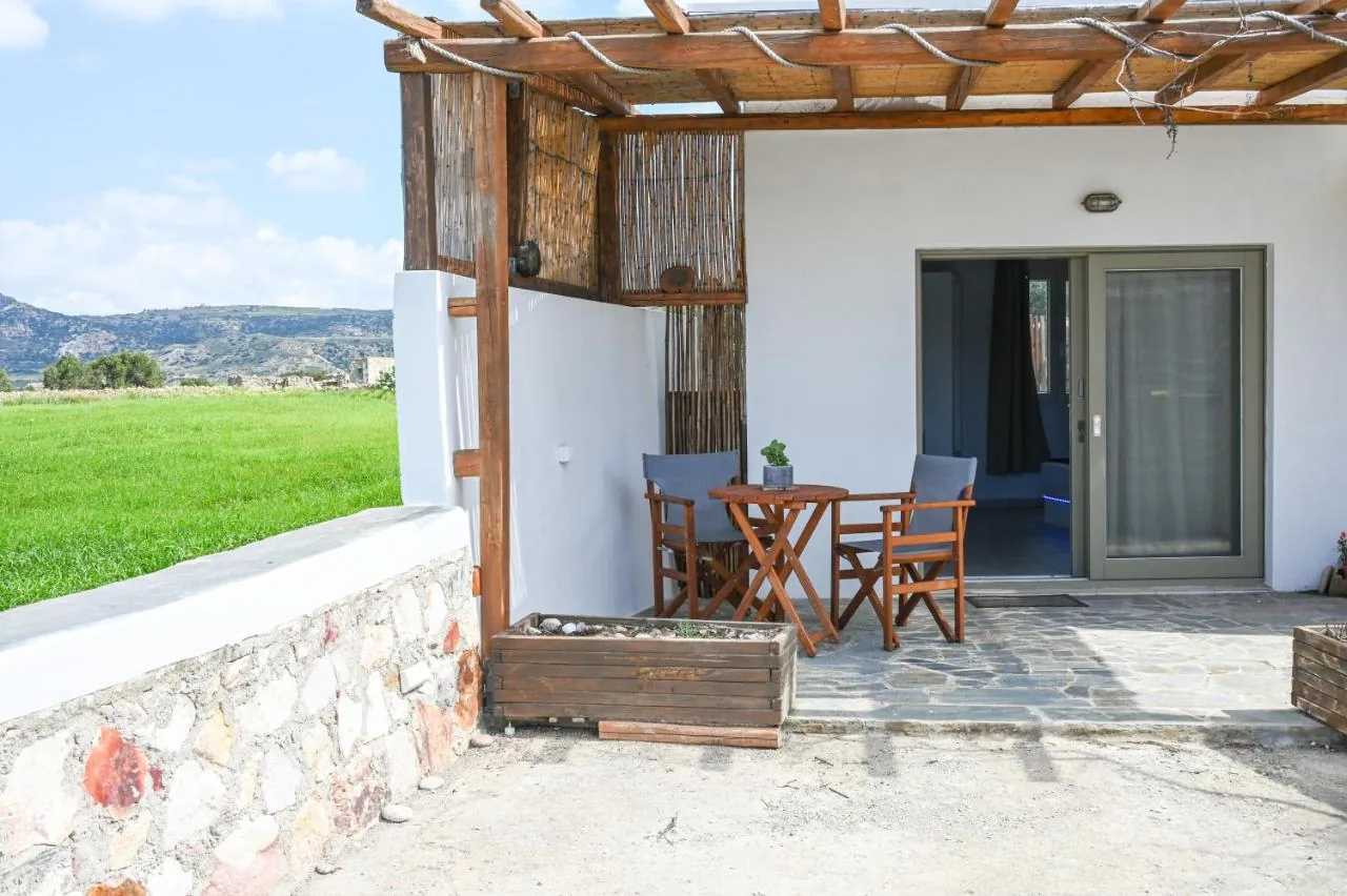 The studio's pergola and stone wall, with a green field and hills beyond