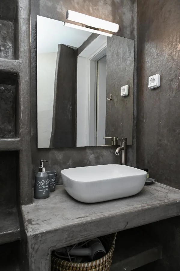 The studio's bathroom: a white basin on a pressed-cement counter, a mirror above